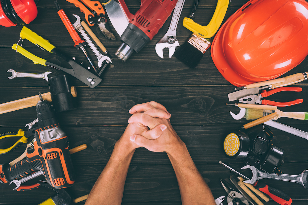 partial view of hands in lock and carpentry equipment around on wooden surface